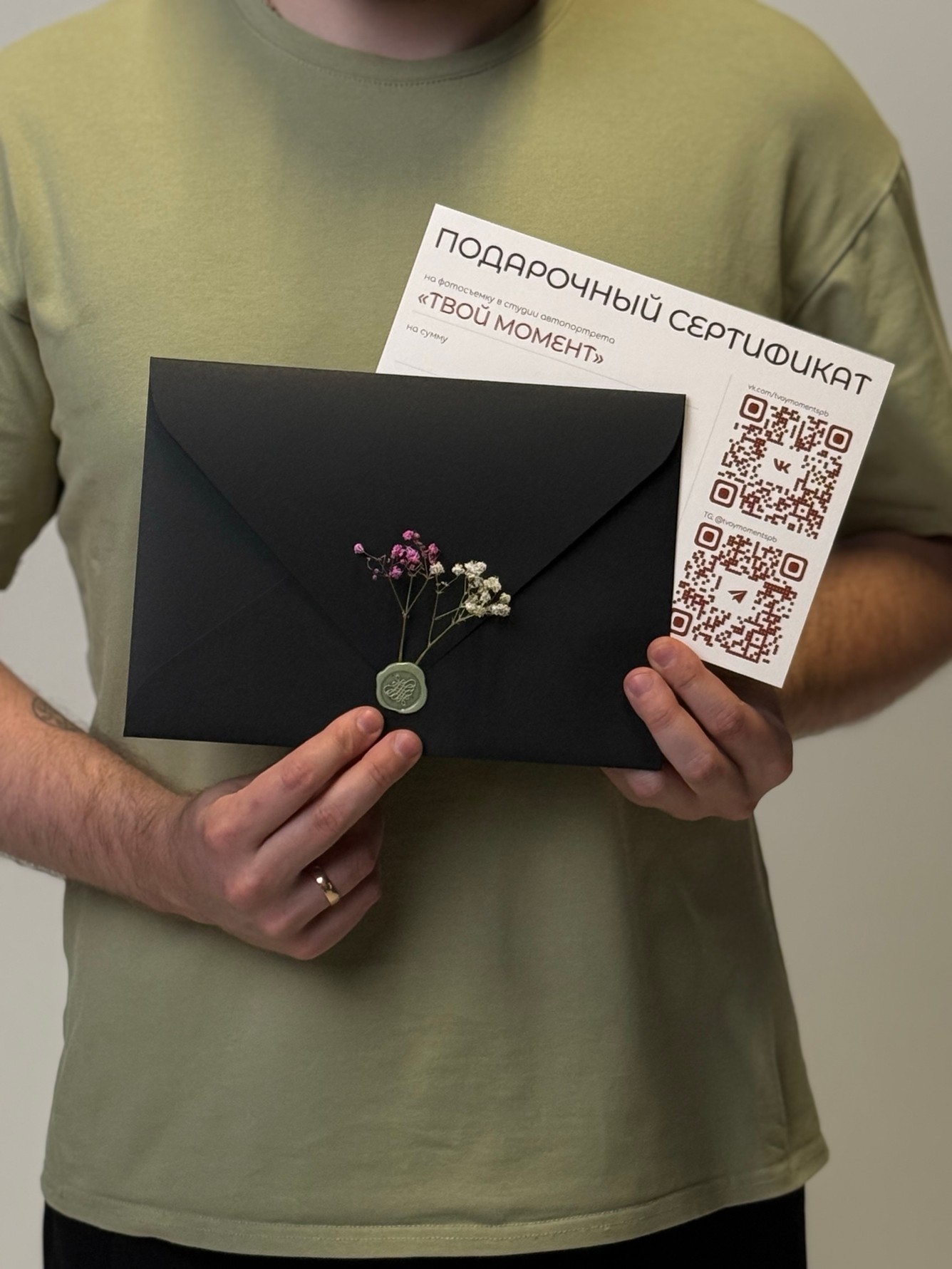 Подарочный сертификат «Твой момент» и черный конверт с сухоцветами в руках
